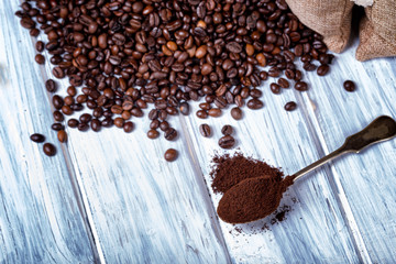Ground coffee in spoon with coffee beans.