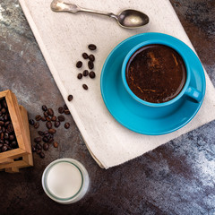 Cup of coffee and wooden containers filled with cofee beans