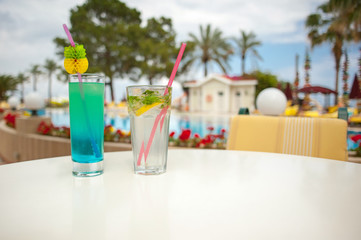 Cool cocktails against the backdrop of palm trees and a swimming pool