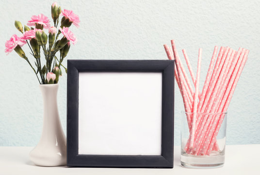 Pink flowers in a vase, paper straws and blank frame