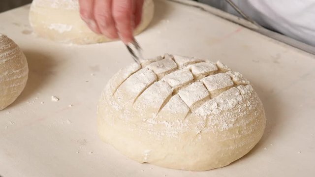 Baker making traditional pattern on the raw ball dough bread