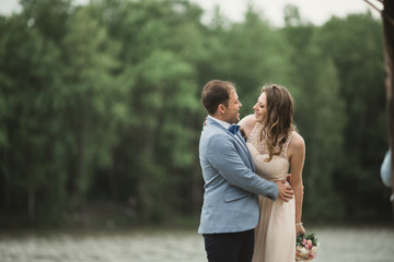 Groom carrying bride near lake and forest