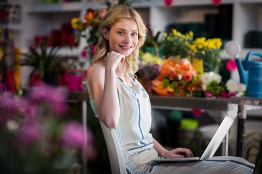 Smiling female florist using laptop in florist shop