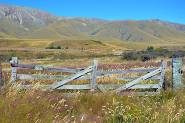 Rustic wooden gate in a meadow with mountains in the distance