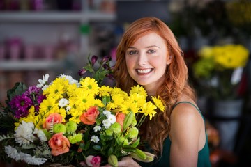 Naklejka premium Happy female florist holding bunch of flowers