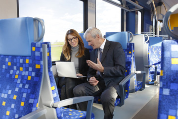 Business people. Businessman and businesswoman working on laptop online on train.