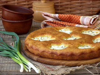 salted pie with cottage cheese and young green garlic on a wooden background