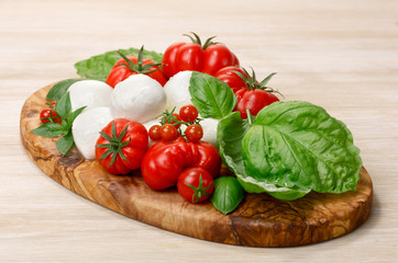 Mozzarella, heirloom tomatoes, basil leaves on a wooden serving