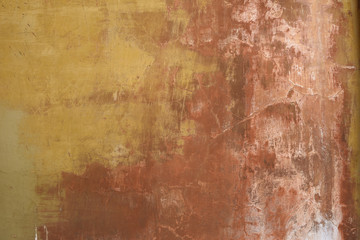 Old weathered and worn stucco wall in ochre and earth colours background