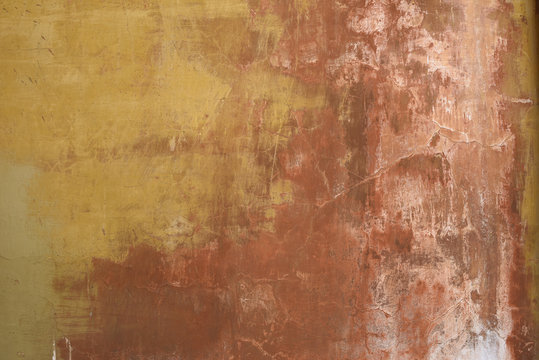 Old weathered and worn stucco wall in ochre and earth colours background