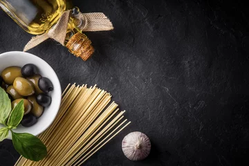 Fototapeten Spaghetti, olives and olive oil on the black stone table © deniskarpenkov