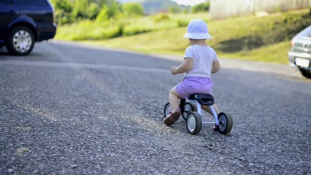 Litle girl riding a bicycle outside in sunny nature