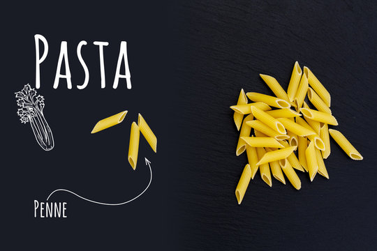 Uncooked Italian pasta Penne on black slate stone background with white lettering, top view