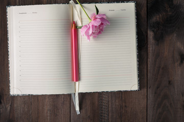 blank page of notebook and pencil ,pink flower on wood backgroun