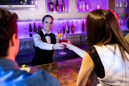 Barmaid serving drink to woman