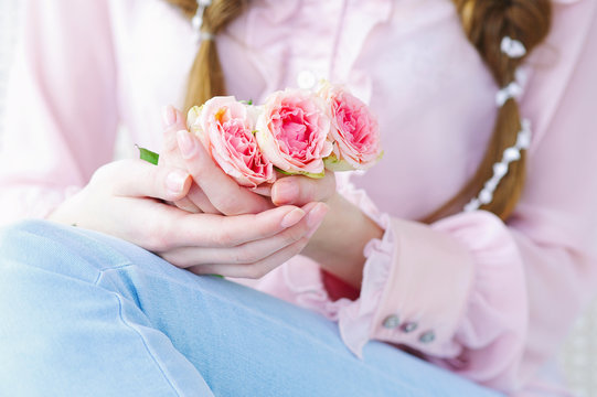 Closeup woman hands with natural manicure holding beautiful delicate branch of pink roses