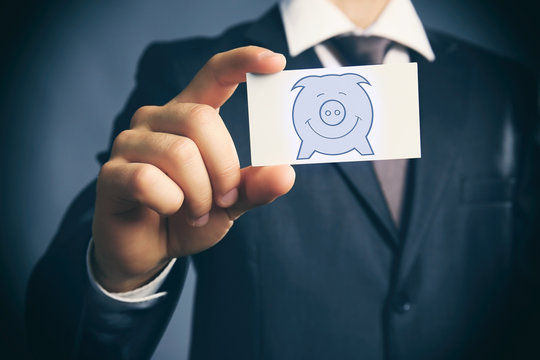 Elegant man in suit holding business card with picture of piggy bank