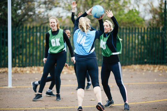 Female netball teams playing match on netball court