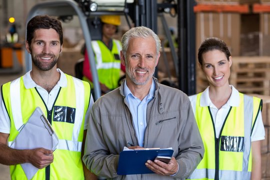 Portrait of manager is posing next to the workers and smiling