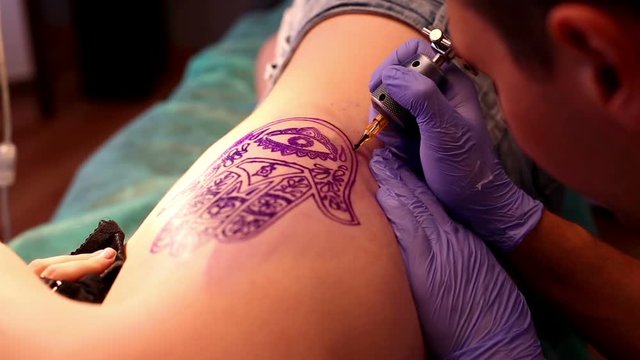 Master makes a tattoo
