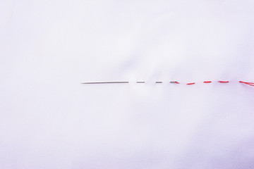 Needle sewing a white  garment with horizontal line