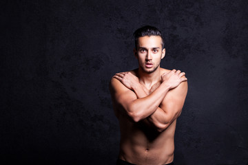 Fototapeta premium Sexy shirtless male model flirting against black background