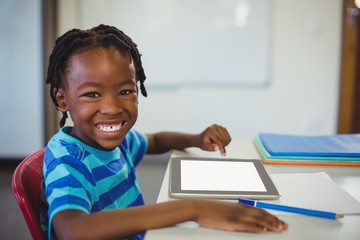Happy schoolboy with digital tablet in classroom