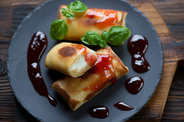 Crepes with cottage cheese stuffing and jam served on a plate