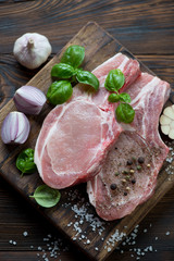Top view of a chopping board with fresh pork meat steaks on bone