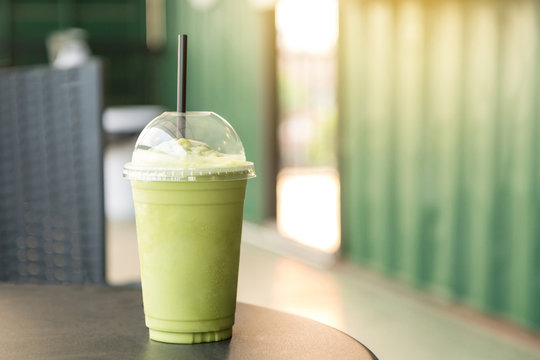 Fototapeta Green tea matcha smoothies in plastic cup. Interior coffee shop. Condensation on a cup (Selective focus and shallow depth of field)