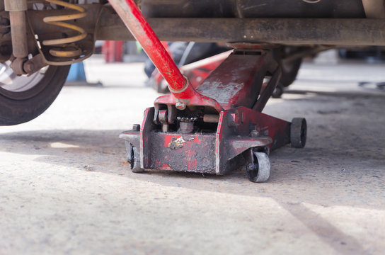 Close Up Shot Of Old Red Car Jack And Removed Wheel Selective Fo