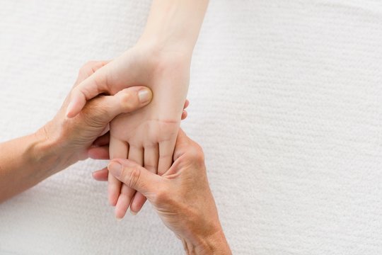 Cropped image of masseur giving hand massage to woman