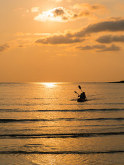 Fototapeta premium Silhouette of a lovely couple on a canoe boat during sunset