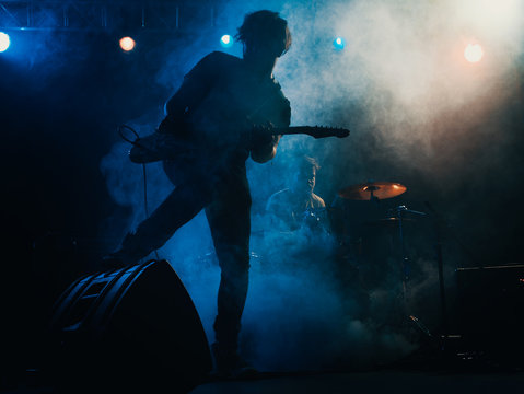 Silhouette of guitar player on stage.