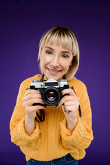 Portrait of young girl with camera over purple background.