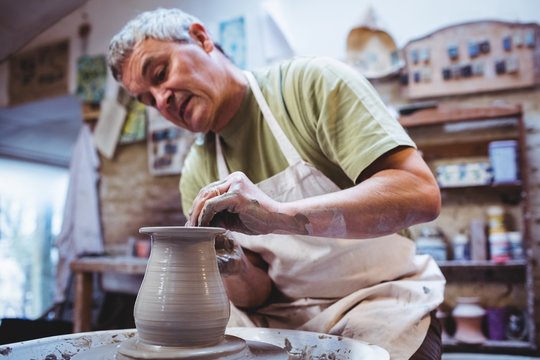 Craftsperson making container in pottery workshop