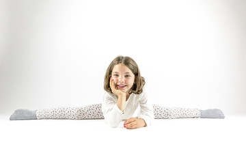 Cute fit athletic girl leans forward in splits on floor, studio shot.