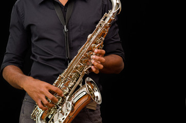 Fototapeta na wymiar Nice hands touching a silver saxophone, black background