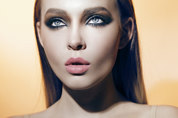 beautiful girl with smoky eyes and blue eyes on the orange background