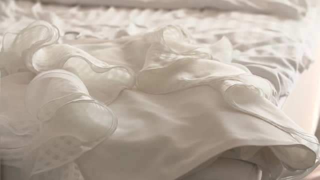Beautiful white wedding dress for bride on bed.