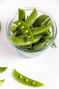 Sugar snap peas in the jar on the white background. 
