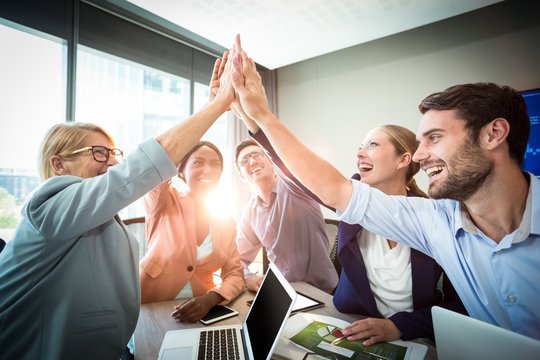 Business people giving high five at desk