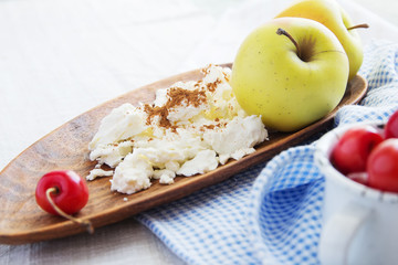 Composition of fruits and berries, cottage cheese. Reason for the longevity is apples, cherries. Fruits and berries, cottage cheese in a bowl on a checkered napkin on the table.