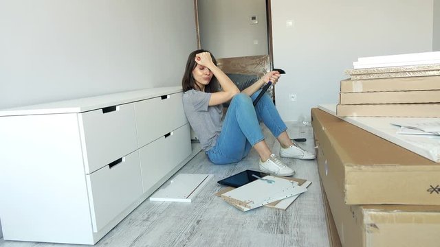 Angry woman during assembling furniture in her new home.
