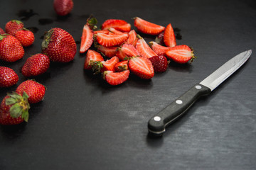 strawberries and knife on black background