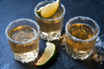 Tequila shot with lime and sea salt on black table