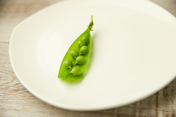 Green pea pod on the  big white plate.