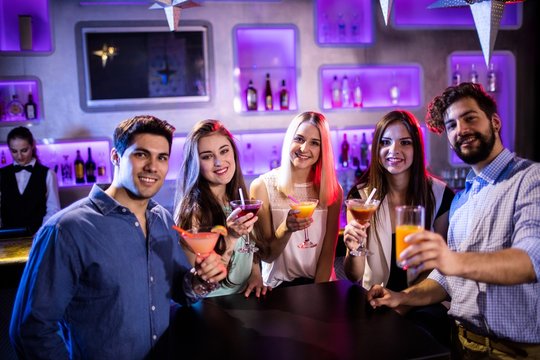 Group of friends showing cocktail at bar counter