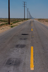 Fototapeta premium A road with a dashed yellow line leads to the horizon in the desert.