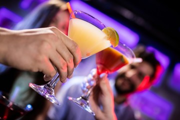 Friends toasting cocktail at bar counter